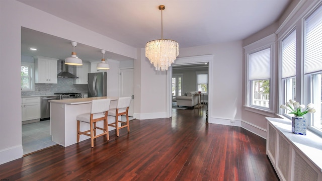 kitchen with pendant lighting, plenty of natural light, white cabinetry, stainless steel appliances, and dark hardwood / wood-style floors