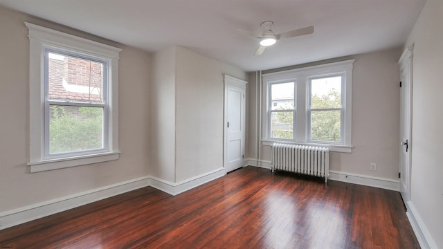 empty room with ceiling fan, radiator heating unit, and dark hardwood / wood-style flooring