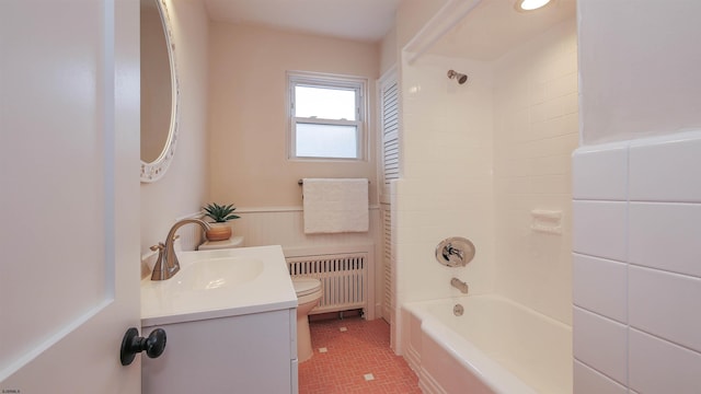 full bathroom with toilet, radiator, vanity, and tiled shower / bath