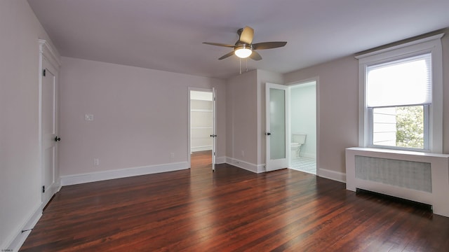 empty room featuring ceiling fan, dark wood-type flooring, and radiator heating unit