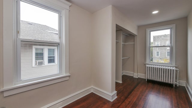 interior space with radiator, a closet, dark hardwood / wood-style flooring, and multiple windows