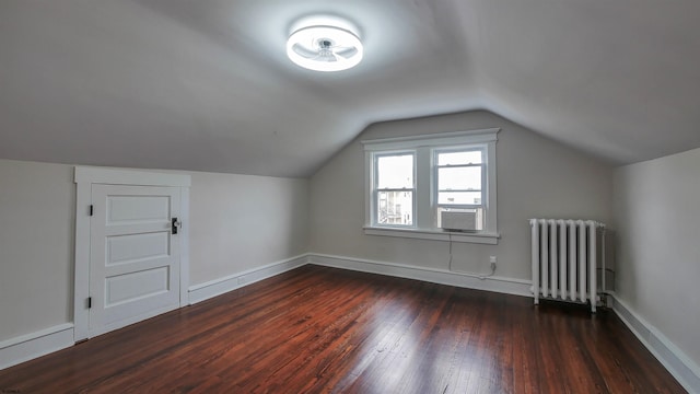 additional living space with dark wood-type flooring, radiator heating unit, lofted ceiling, and cooling unit