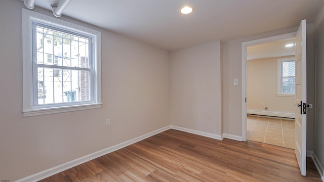 spare room with a baseboard heating unit and wood-type flooring