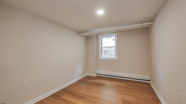 unfurnished room featuring light hardwood / wood-style floors and a baseboard radiator