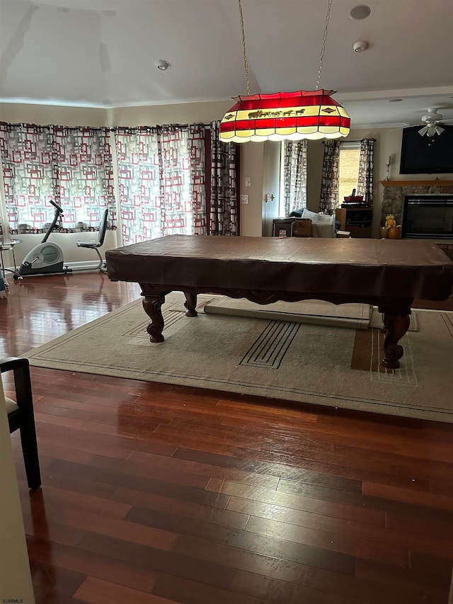 recreation room featuring ceiling fan, a stone fireplace, wood-type flooring, and billiards