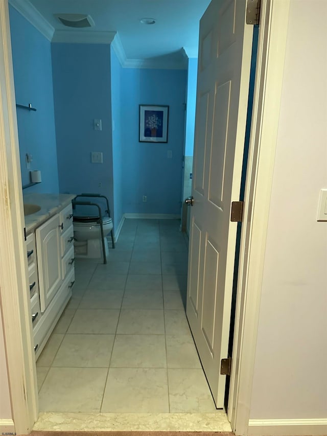 corridor with crown molding and light tile patterned floors