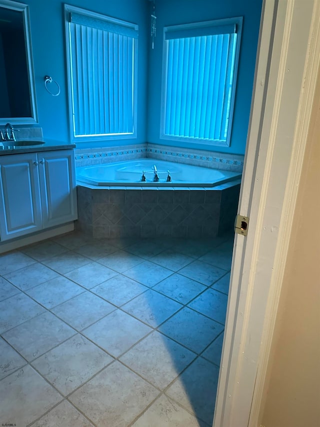 bathroom with tile patterned flooring, a relaxing tiled tub, and vanity