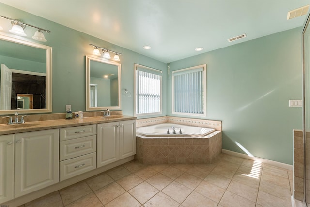 bathroom with a relaxing tiled tub, tile patterned flooring, and vanity