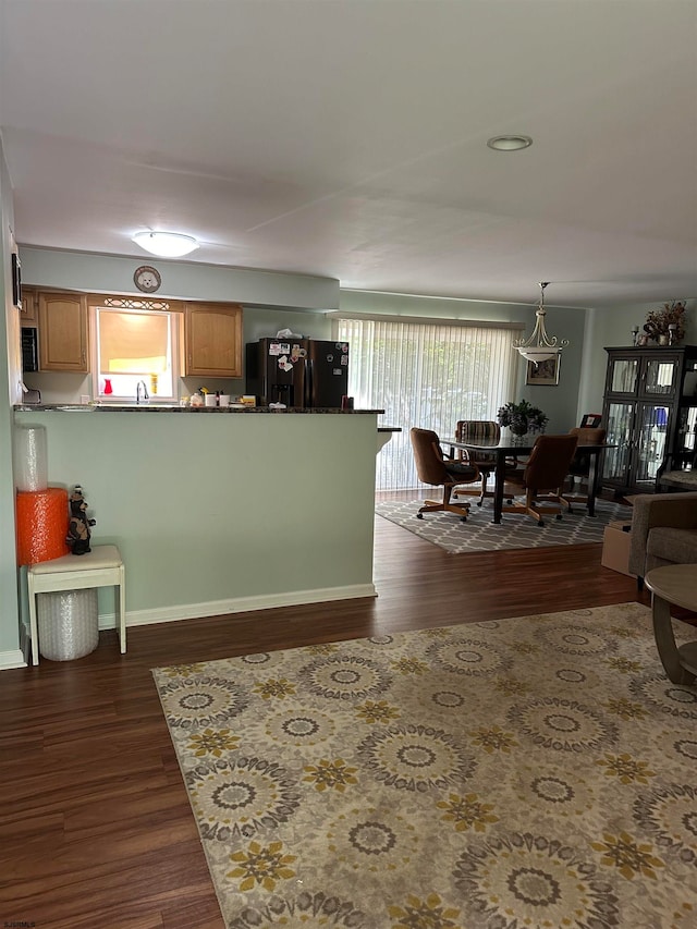 kitchen featuring hanging light fixtures, dark hardwood / wood-style flooring, kitchen peninsula, and black appliances