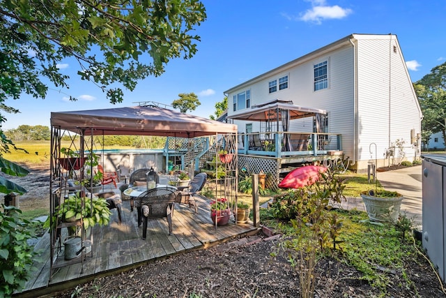 rear view of property with a deck and a gazebo