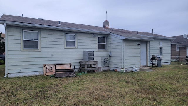 back of house with cooling unit and a lawn