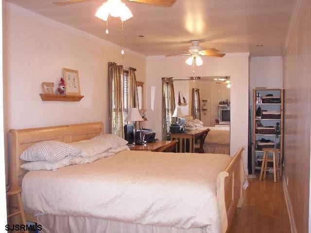 bedroom with ornamental molding, hardwood / wood-style floors, and ceiling fan