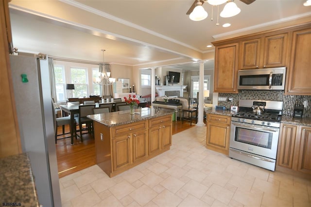 kitchen featuring pendant lighting, dark stone countertops, decorative backsplash, appliances with stainless steel finishes, and a center island