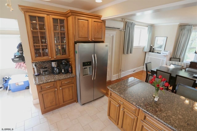 kitchen with dark stone counters, backsplash, stainless steel fridge, and ornamental molding