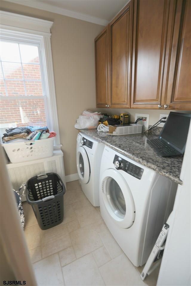 laundry area featuring washer and dryer, crown molding, and cabinets