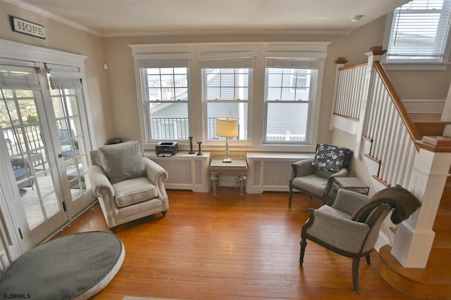 living area with radiator, light wood-type flooring, and ornamental molding