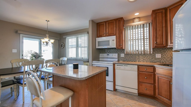 kitchen featuring a center island, white appliances, decorative light fixtures, light tile patterned floors, and backsplash