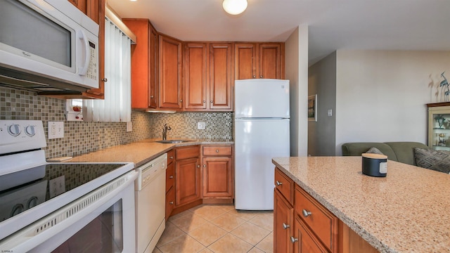 kitchen with light stone countertops, tasteful backsplash, white appliances, sink, and light tile patterned floors