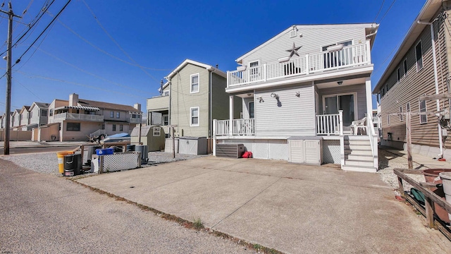 rear view of house featuring a porch, a balcony, and central AC