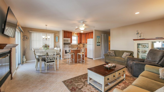 living room with light tile patterned flooring and ceiling fan with notable chandelier