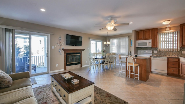 tiled living room featuring ceiling fan with notable chandelier and a healthy amount of sunlight