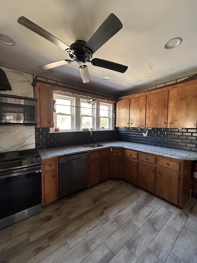 kitchen featuring ceiling fan, light hardwood / wood-style flooring, sink, backsplash, and appliances with stainless steel finishes