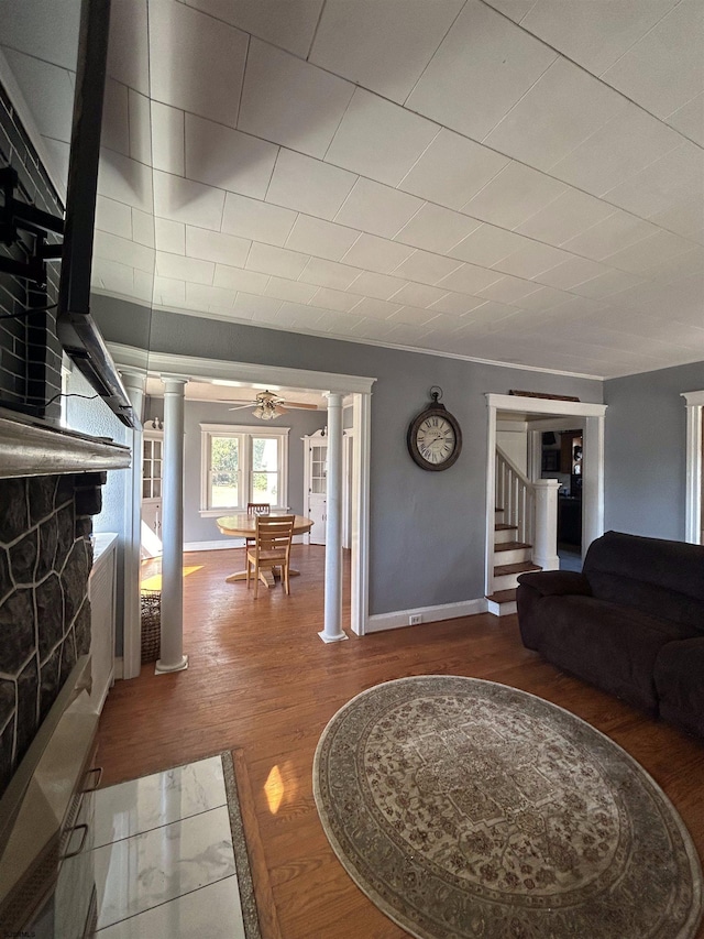 living room with wood-type flooring, decorative columns, and ceiling fan