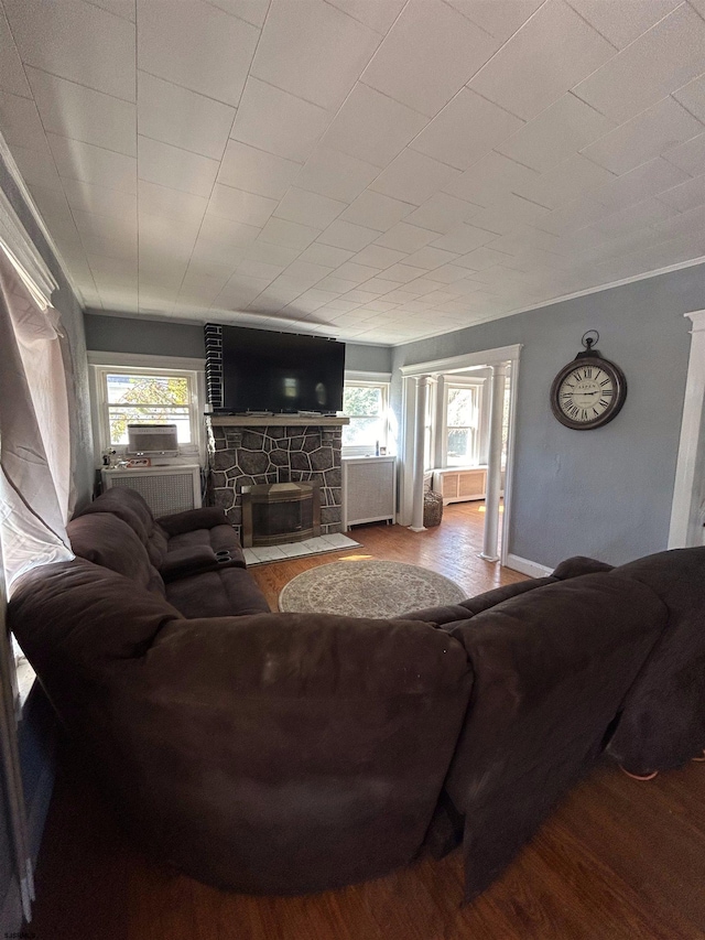 living room featuring a fireplace, wood-type flooring, and crown molding