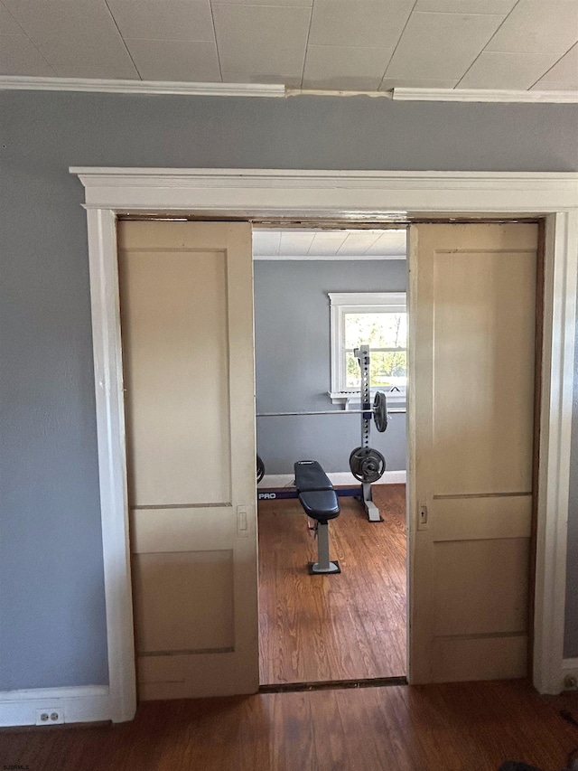 exercise room with ornamental molding and wood-type flooring