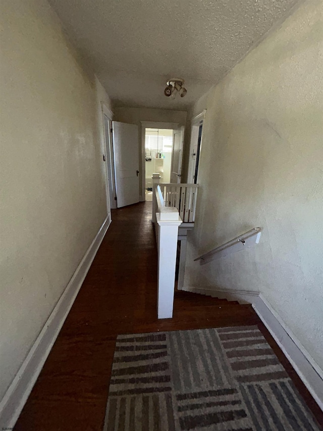 hallway with dark wood-type flooring and a textured ceiling