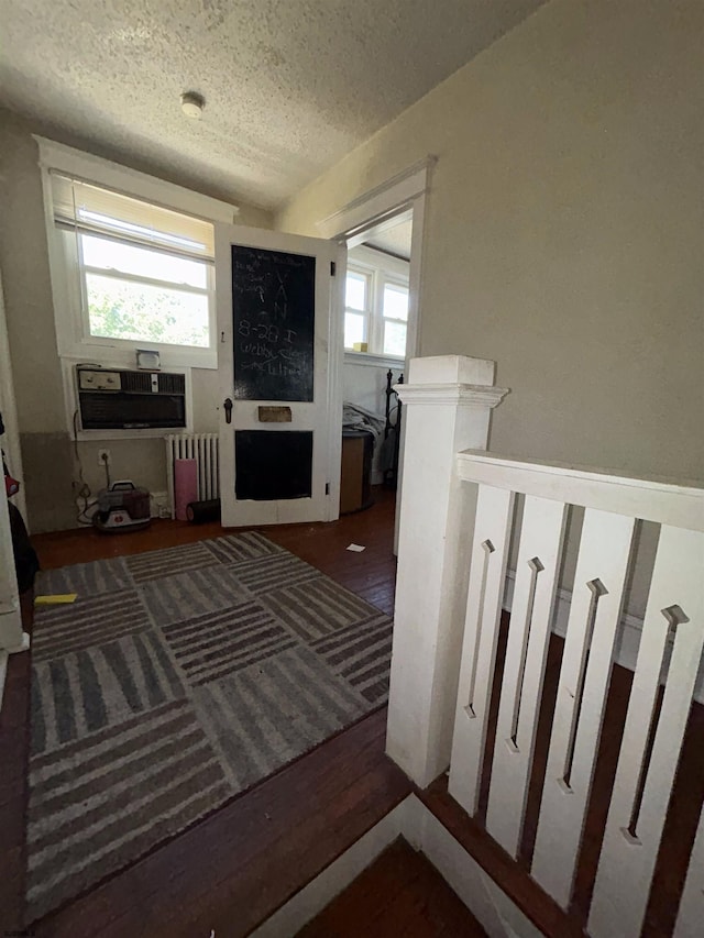 interior space featuring dark hardwood / wood-style flooring, a textured ceiling, and radiator