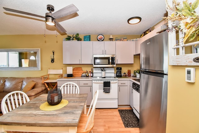 kitchen featuring appliances with stainless steel finishes, light wood-type flooring, white cabinetry, and a textured ceiling