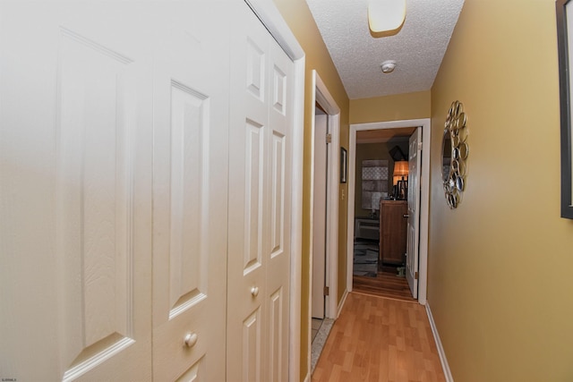 corridor with a textured ceiling and light wood-type flooring