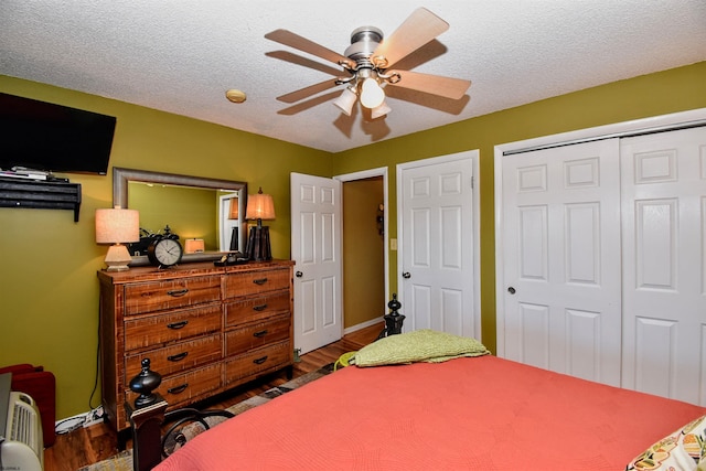 bedroom featuring a closet, dark hardwood / wood-style flooring, a textured ceiling, and ceiling fan