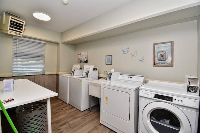 clothes washing area featuring separate washer and dryer, wood walls, and light hardwood / wood-style floors