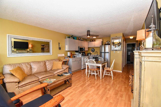 living room featuring a textured ceiling, sink, and light hardwood / wood-style flooring