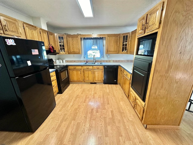 kitchen featuring sink, light hardwood / wood-style flooring, crown molding, a textured ceiling, and black appliances