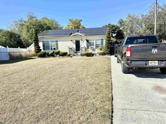 bungalow-style home featuring solar panels, a front yard, and fence