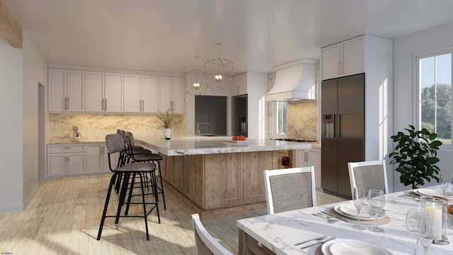 kitchen with decorative backsplash, white cabinets, hanging light fixtures, light hardwood / wood-style flooring, and appliances with stainless steel finishes