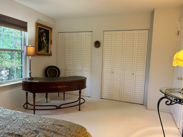 carpeted bedroom featuring multiple closets and a textured ceiling