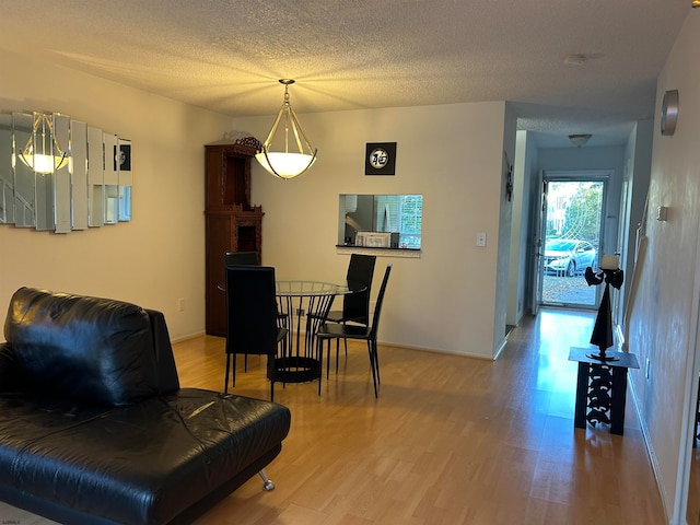 dining area featuring light wood-type flooring and a textured ceiling