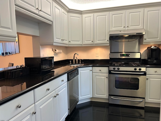 kitchen featuring white cabinets, appliances with stainless steel finishes, sink, and dark tile patterned floors