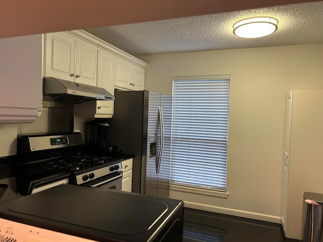 kitchen with stainless steel appliances, white cabinets, dark tile patterned floors, and a textured ceiling