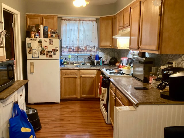 kitchen featuring light wood-type flooring, sink, white appliances, and tasteful backsplash