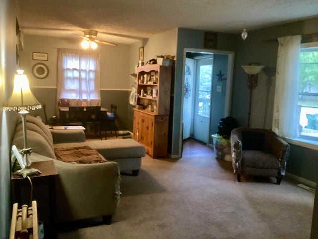 living room featuring ceiling fan, carpet flooring, and a wealth of natural light