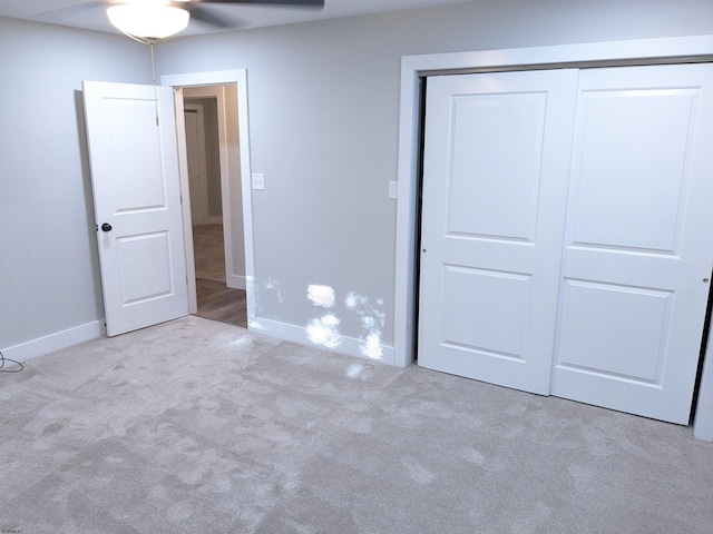 unfurnished bedroom with ceiling fan, light colored carpet, and a closet