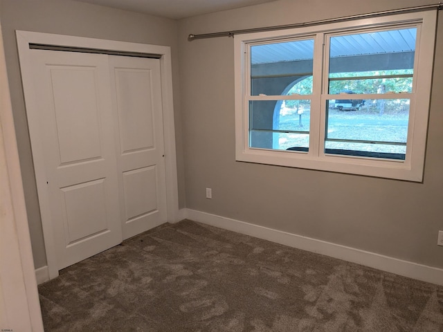 unfurnished bedroom with a closet and dark colored carpet