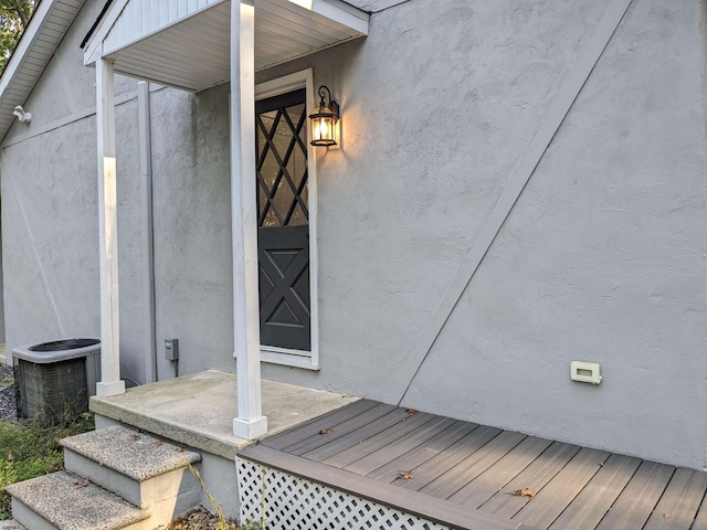 view of exterior entry featuring a deck and central air condition unit