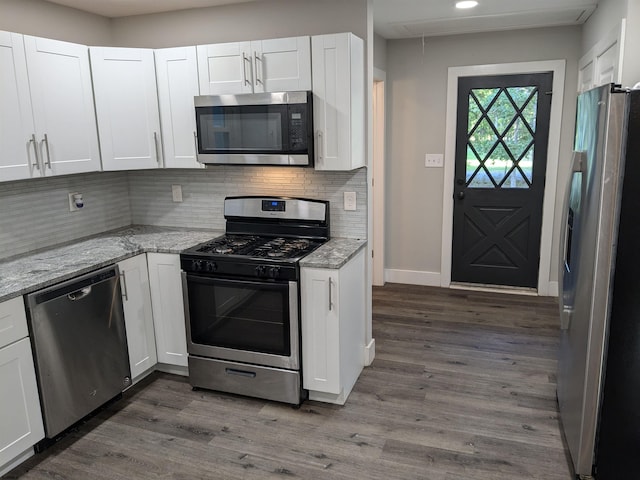 kitchen with stainless steel appliances, light stone countertops, dark hardwood / wood-style floors, and white cabinetry