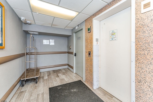 hall with a drop ceiling and hardwood / wood-style floors